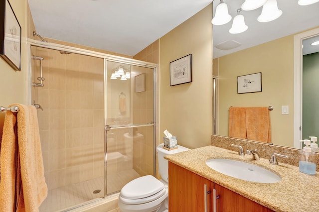 bathroom featuring a shower stall, toilet, and vanity