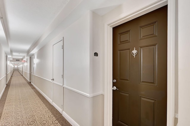 hallway featuring carpet flooring and baseboards