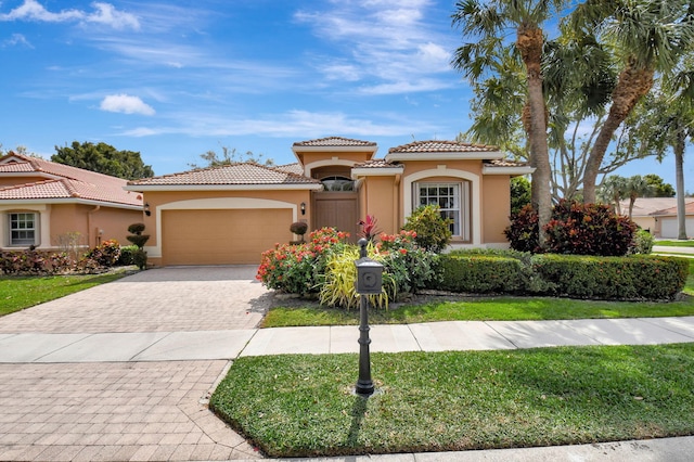 mediterranean / spanish-style house with a front lawn, decorative driveway, an attached garage, and stucco siding