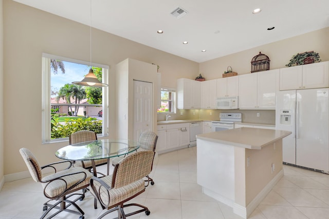 kitchen with light tile patterned floors, white appliances, a sink, visible vents, and light countertops