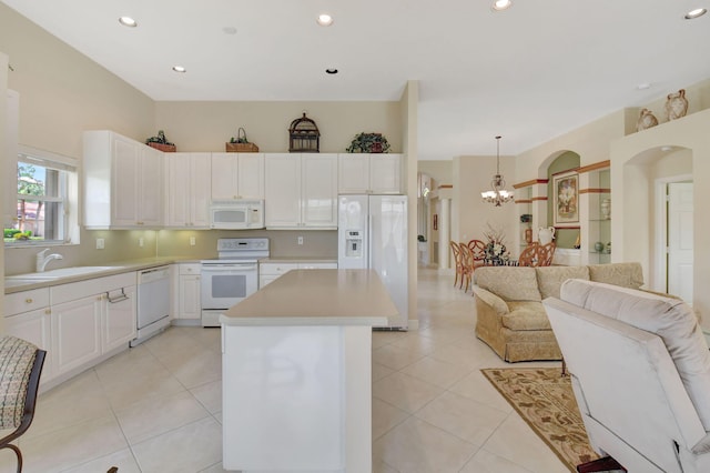 kitchen featuring white appliances, open floor plan, a center island, light countertops, and a sink