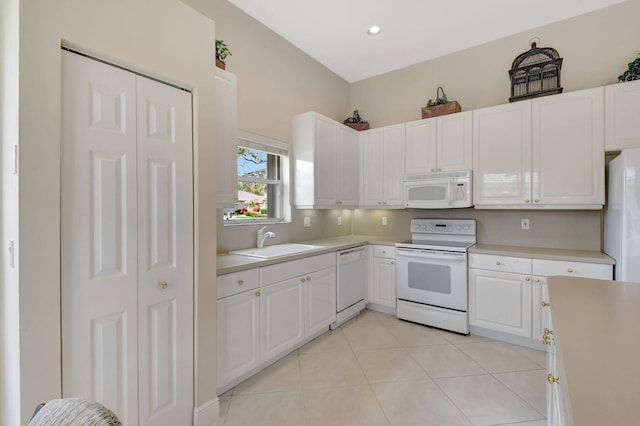 kitchen featuring white appliances, light countertops, a sink, and white cabinets