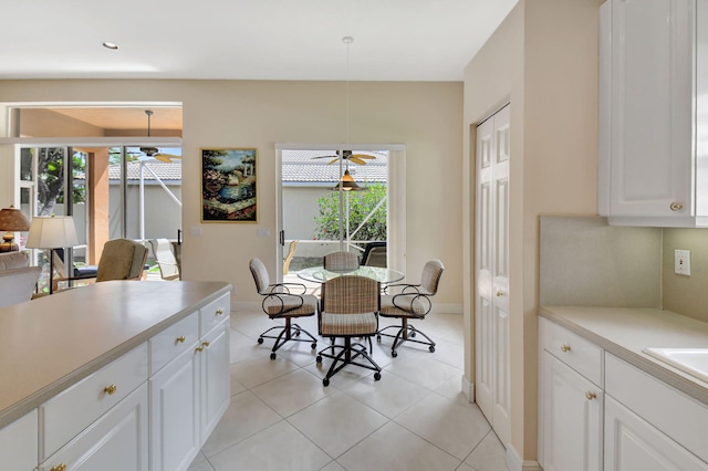 dining space with ceiling fan, baseboards, and light tile patterned flooring