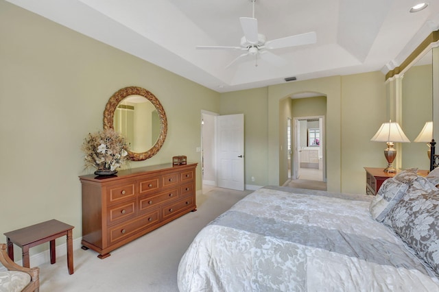 bedroom featuring arched walkways, a raised ceiling, visible vents, and light colored carpet