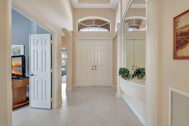 entryway featuring arched walkways, visible vents, baseboards, and light tile patterned floors