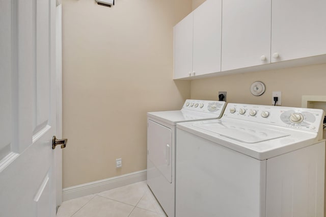 laundry room featuring washer and dryer, cabinet space, baseboards, and light tile patterned flooring