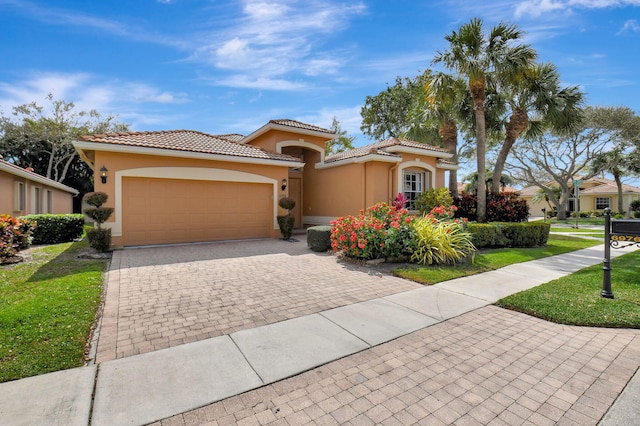 mediterranean / spanish-style home with a garage, decorative driveway, a tile roof, and stucco siding