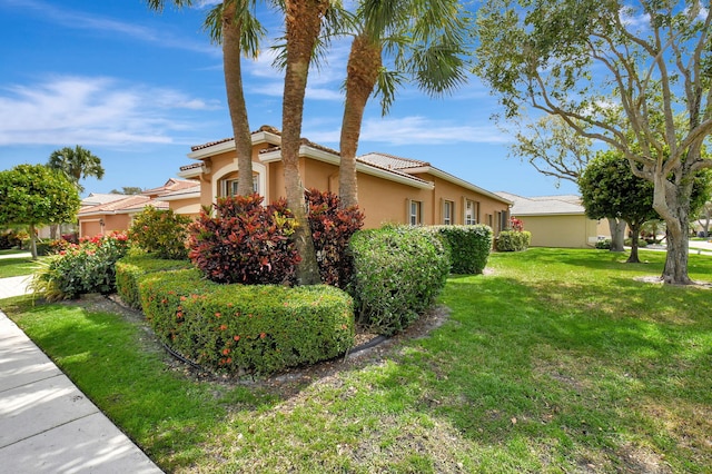 view of home's exterior featuring a tile roof, a lawn, and stucco siding