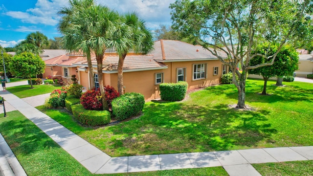 ranch-style house with a front yard, a tile roof, and stucco siding