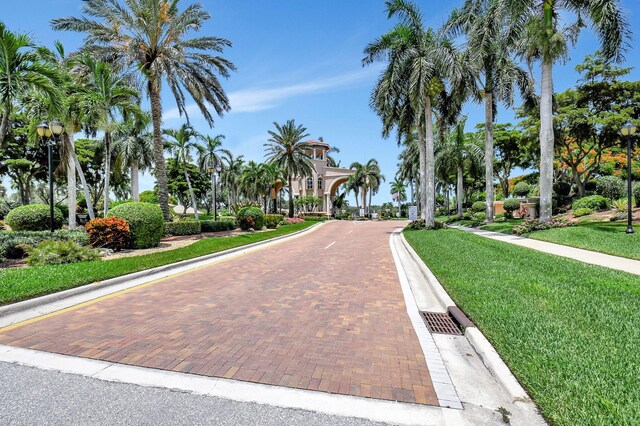 view of community with decorative driveway and a lawn