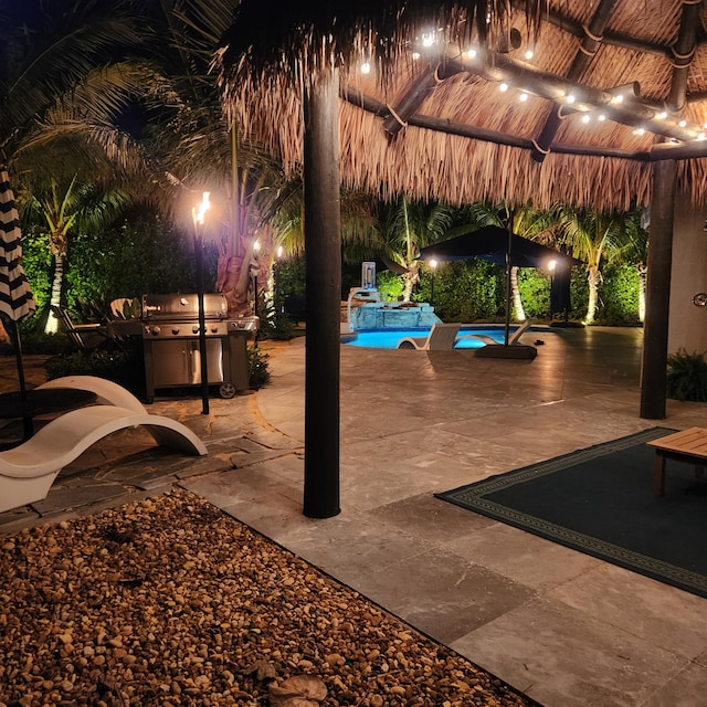 patio at twilight with an outdoor pool and grilling area