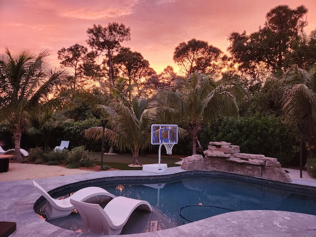 pool at dusk featuring a patio