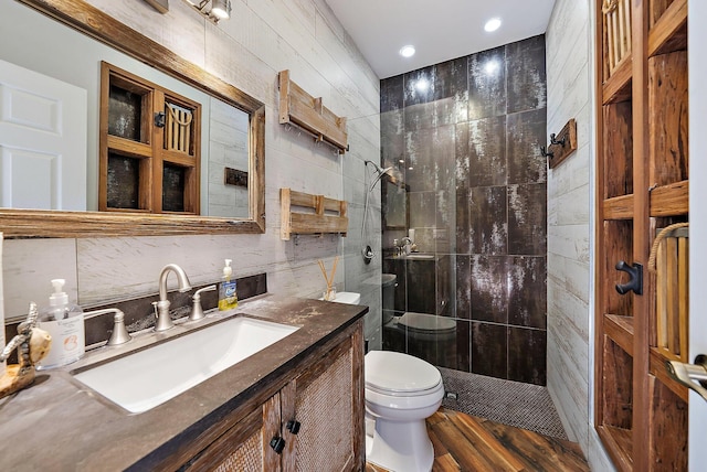 bathroom featuring tasteful backsplash, toilet, vanity, a walk in shower, and tile walls