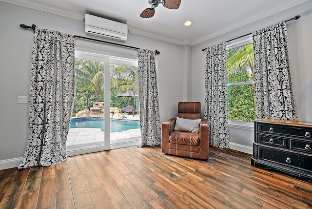 living area with ornamental molding, a wall mounted air conditioner, plenty of natural light, and wood finished floors