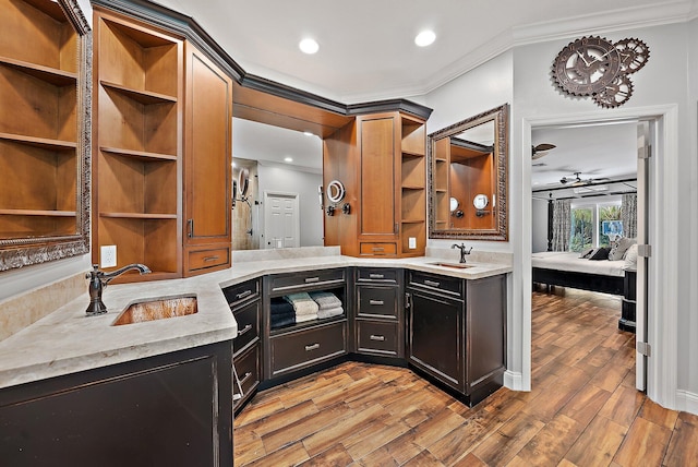 kitchen featuring open shelves, a sink, light wood-style flooring, and crown molding