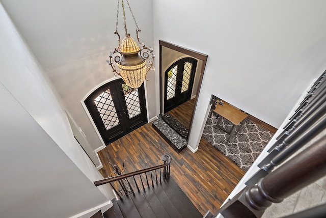 entrance foyer with french doors, a towering ceiling, baseboards, and wood finished floors