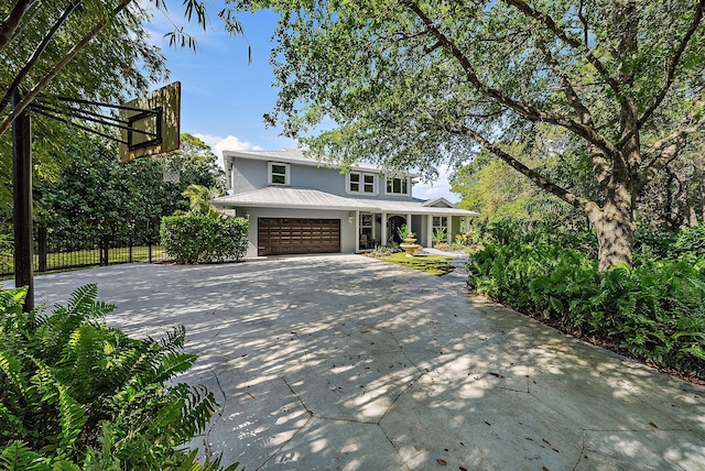 view of front of property featuring stucco siding, concrete driveway, fence, metal roof, and a garage