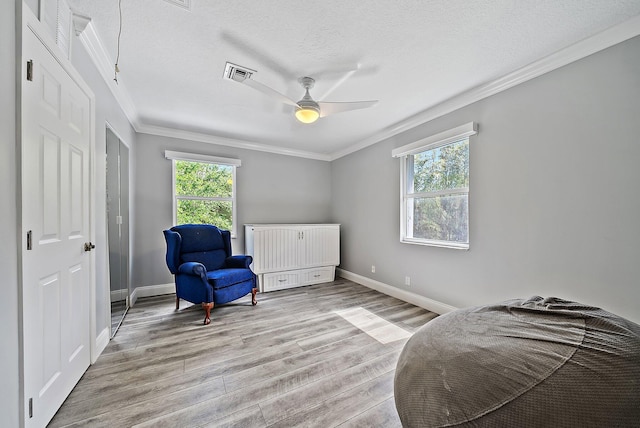 bedroom with crown molding, visible vents, a textured ceiling, light wood-type flooring, and baseboards