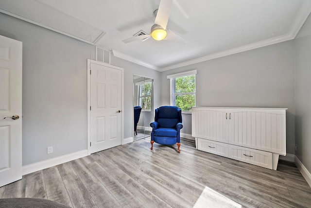 living area with attic access, crown molding, baseboards, and wood finished floors