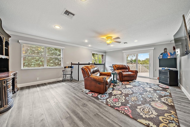 living area with ornamental molding, visible vents, baseboards, and wood finished floors