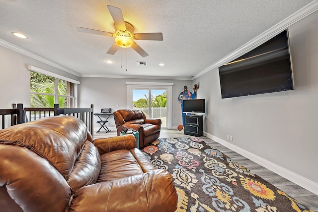 living area featuring baseboards, visible vents, crown molding, and wood finished floors