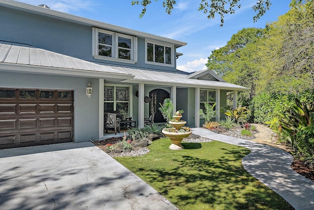 view of front of home featuring stucco siding, an attached garage, a front yard, a standing seam roof, and metal roof