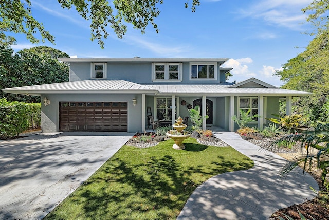 view of front of property featuring an attached garage, concrete driveway, stucco siding, a standing seam roof, and a front yard