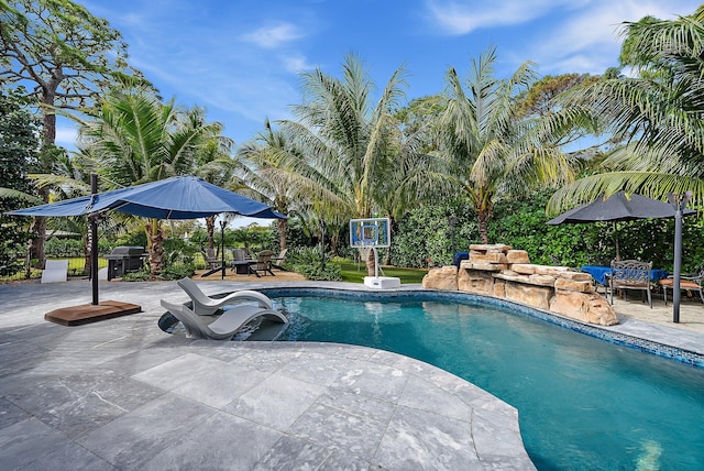 pool with a patio area and a grill