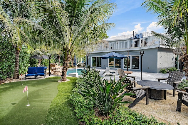 back of property featuring a balcony, stucco siding, an outdoor pool, and a patio