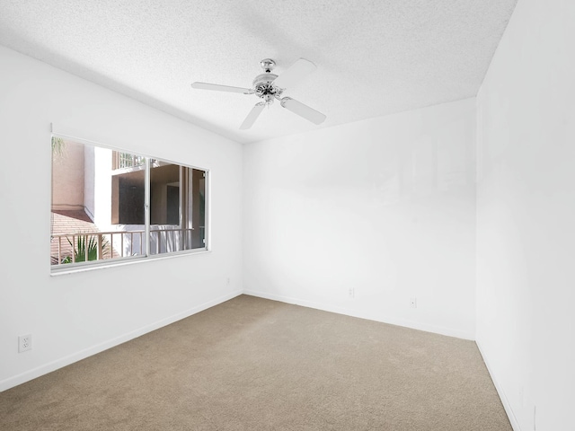 empty room with carpet flooring, a ceiling fan, baseboards, and a textured ceiling