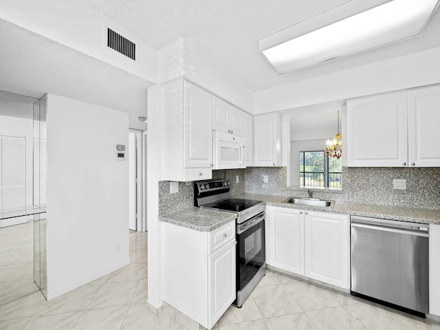 kitchen featuring a notable chandelier, a sink, white cabinetry, stainless steel appliances, and visible vents