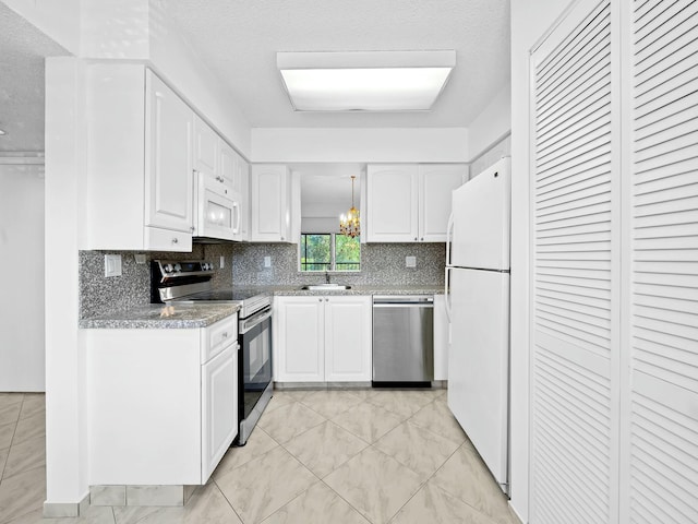 kitchen with a notable chandelier, a sink, white cabinetry, tasteful backsplash, and appliances with stainless steel finishes