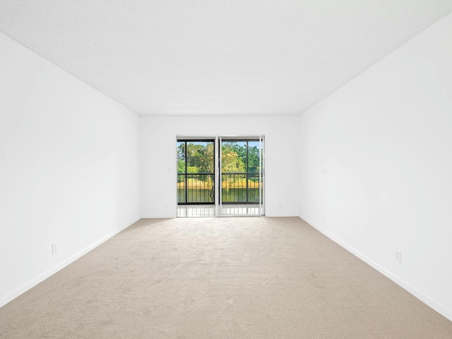 carpeted empty room featuring baseboards