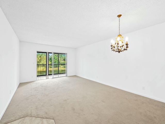 empty room with baseboards, a textured ceiling, a chandelier, and carpet