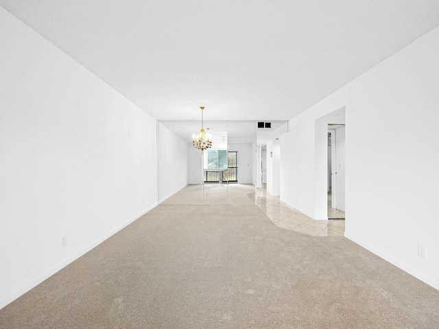 unfurnished room featuring baseboards, visible vents, a chandelier, and light colored carpet