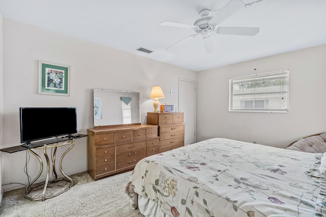 bedroom featuring a ceiling fan, visible vents, and light colored carpet