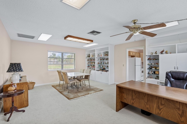 home office featuring baseboards, visible vents, a textured ceiling, and light colored carpet