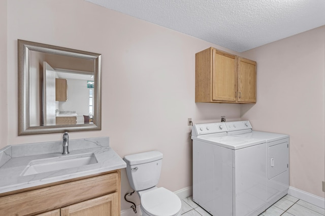 bathroom featuring a textured ceiling, tile patterned flooring, washing machine and clothes dryer, and toilet