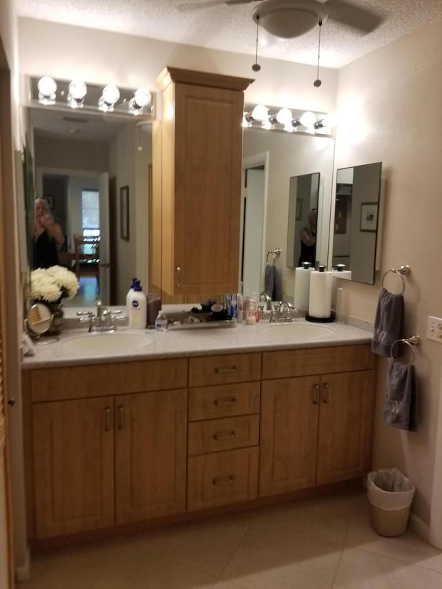 bathroom with a textured ceiling, double vanity, tile patterned flooring, and a sink