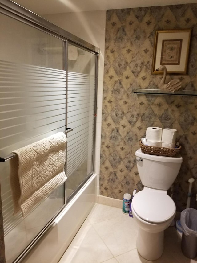 full bath featuring enclosed tub / shower combo, tile patterned flooring, toilet, baseboards, and wallpapered walls