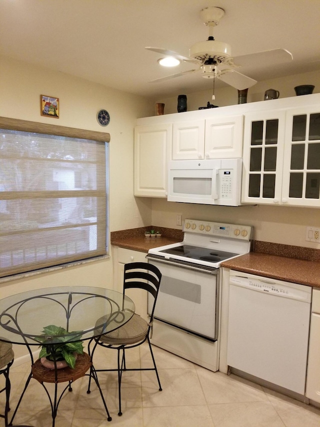 kitchen featuring white appliances, light tile patterned floors, dark countertops, ceiling fan, and white cabinetry