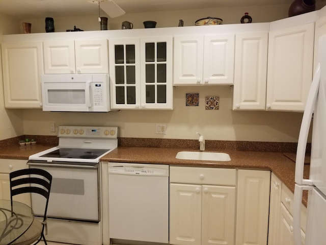 kitchen with white appliances, white cabinetry, and a sink