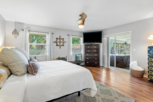 bedroom featuring access to outside, wood finished floors, and a ceiling fan