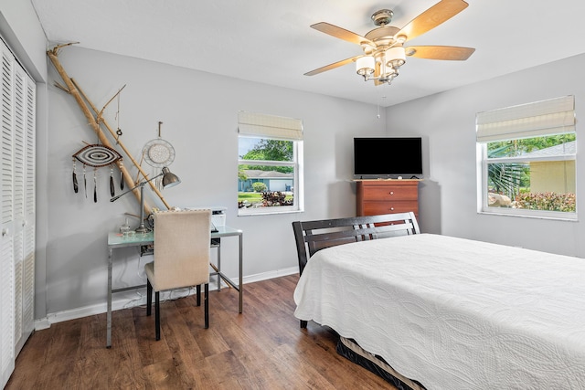 bedroom with baseboards, multiple windows, ceiling fan, and wood finished floors