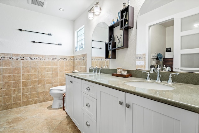 full bathroom featuring toilet, tile walls, visible vents, and a sink