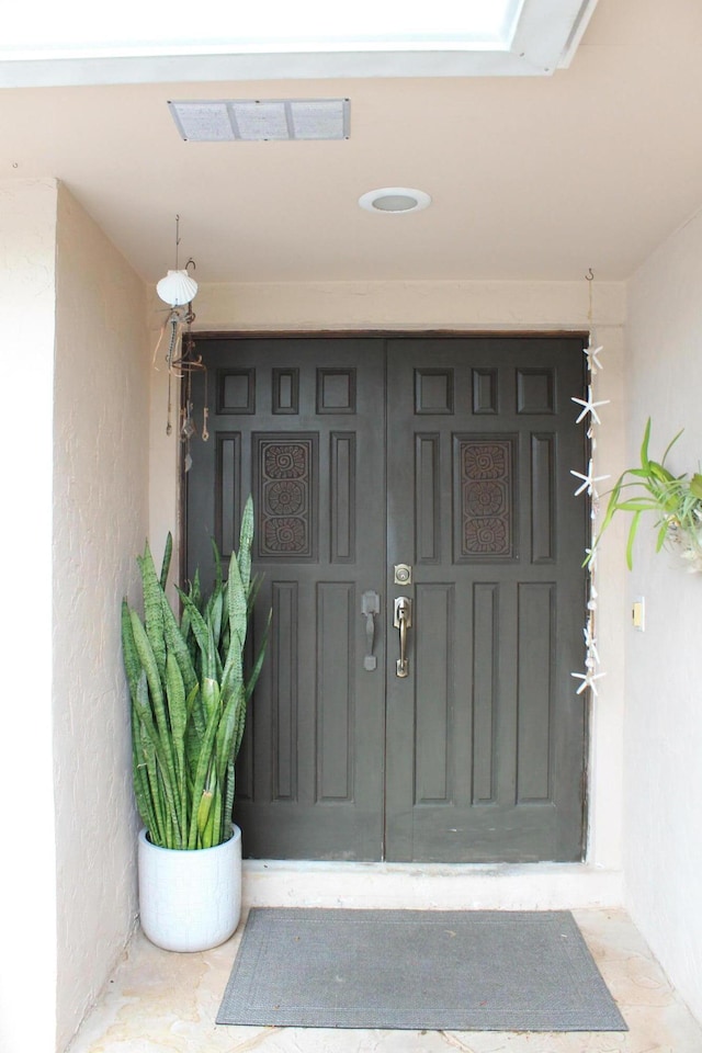 property entrance featuring visible vents and stucco siding