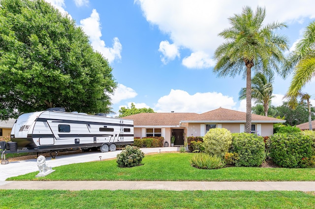 ranch-style house with concrete driveway, a front yard, and stucco siding