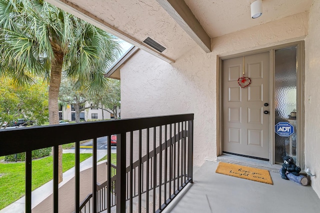 entrance to property featuring a balcony and stucco siding