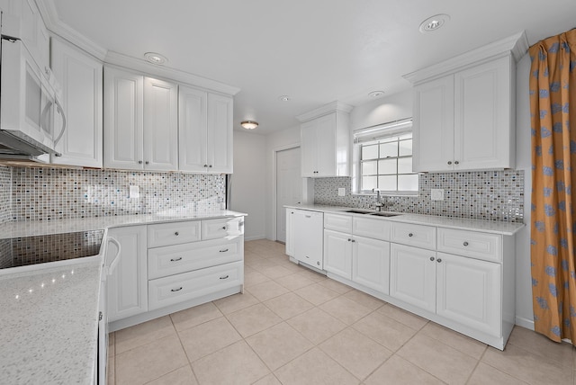 kitchen featuring white appliances, white cabinets, a sink, and light tile patterned floors