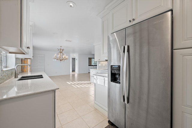 kitchen featuring light tile patterned floors, white cabinets, a sink, stainless steel refrigerator with ice dispenser, and backsplash